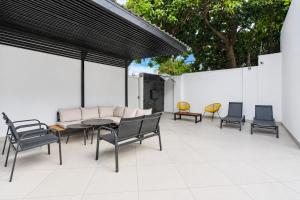 a patio with a table and chairs and a white wall at Hunni Hotel Melrose Edge in Johannesburg