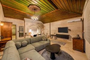 a living room with a couch and a tv at Stone House Cave Hotel in Göreme