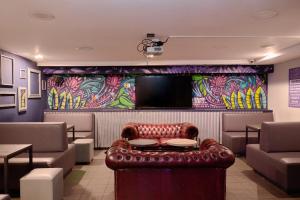 a waiting room with a leather chair and a tv at a&o Edinburgh City in Edinburgh