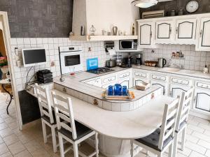 a kitchen with white cabinets and a table and chairs at Charmant et sans chichis in Montlibert