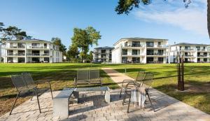 two chairs and a table in a park with buildings at Appartement Haffperle-Oase am Haff in Garz