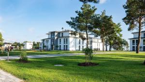 a large white house with trees in the yard at Appartement Haffperle-Oase am Haff in Garz
