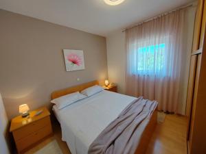 a bedroom with a white bed and a window at Apartments Damir in Sveti Ivan Dobrinjski