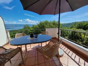 a table and chairs on a balcony with an umbrella at Apartments Damir in Sveti Ivan Dobrinjski