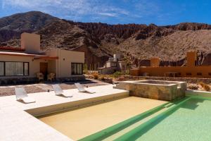 a house with a pool and mountains in the background at Alma de Purmamarca in Purmamarca