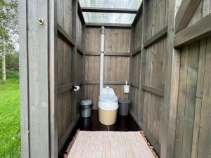 a bathroom with a toilet in a wooden building at CEPĻI Glempings in Dunte