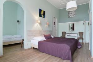 Schlafzimmer mit einem lila Bett, einem Tisch und Stühlen in der Unterkunft Hotel Corel in Scheveningen