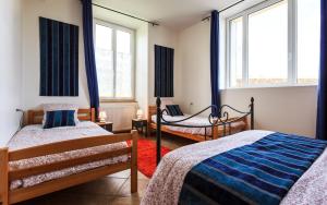 a bedroom with two beds and two windows at Le Clos Auvergnat in Tauves