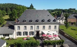 a large white house with tables and umbrellas in front of it at Le Clos Auvergnat in Tauves +10 photos