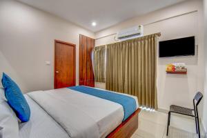 a bedroom with a bed and a window with a television at AVN Comforts Mysore in Mysore