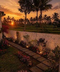 a stone wall with flowers and lights in a yard at Bale Bangket Homestay in Tetebatu +15 photos