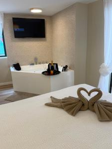 a bed with a heart towel on it with a bath tub at El Rincón de Mateo in Combarro
