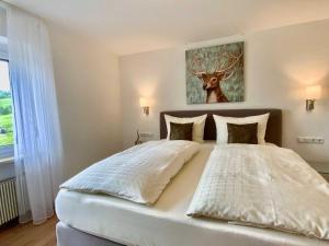 a bedroom with a large bed with a deer painting on the wall at Hubertushof in Jungholz
