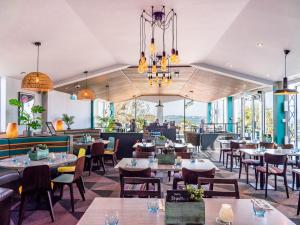 a restaurant with tables and chairs and chandeliers at Beverley Park in Goodrington