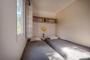two beds sitting in a room with a window at Camping 4 étoiles - Piscine - ccbfiee in Olmeto