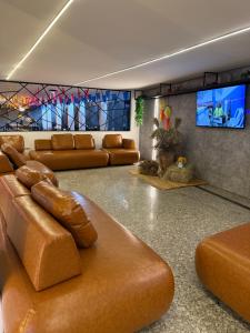 a living room with brown leather furniture and a flat screen tv at Hotel do Vale in Campina Grande