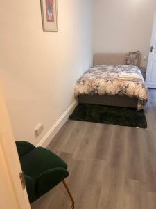 a bedroom with a bed and a green chair at Perfectspot in Tilbury