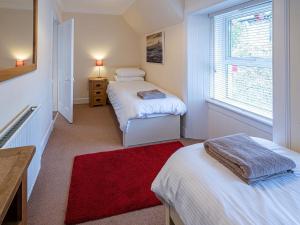a small bedroom with two beds and a red rug at Edengrove in Aberfeldy