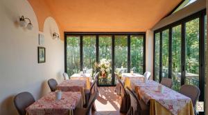 ein Esszimmer mit Tischen und Stühlen und großen Fenstern in der Unterkunft Le Volpaie in San Gimignano