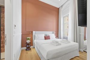 a bedroom with a white bed and a wall at Hospi Living Empire Suites in Heraklio