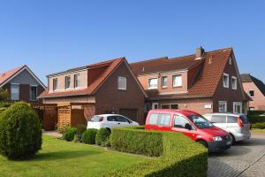 two cars parked in front of a house at Ferienwohnungen Haus Saathoff in Bensersiel