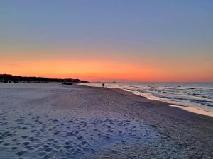 a beach at sunset with a person standing in the water at Ferienzimmer Gleißner in Ahlbeck