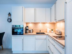 a white kitchen with white cabinets and appliances at Bernsteinquartier - Wohnung 87 in Kölpinsee