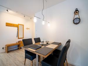 a dining room table with chairs and a clock on the wall at Bernsteinquartier - Wohnung 87 in Kölpinsee