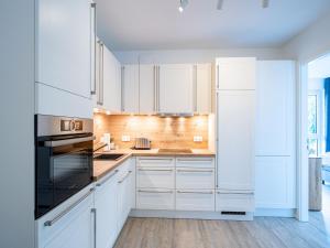 a white kitchen with white cabinets and appliances at Bernsteinquartier - Wohnung 87 in Kölpinsee