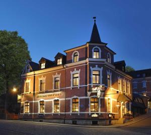 a large brick building with a tower on a street at Hotel zur Post in Schönheide