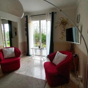 a living room with two red chairs and a television at Mont Joly Gîte in Soumont-Saint-Quentin
