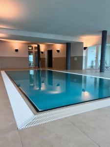 a large swimming pool with blue water in a building at Residenz Bollwark 2 2 in Olpenitz