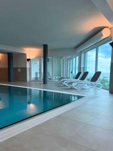 a swimming pool in a building with chairs at Residenz Bollwark 2 2 in Olpenitz