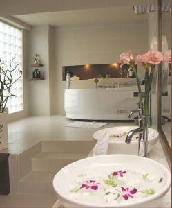 a bathroom with a sink and a tub with flowers at Asia Hotel Hue in Hue