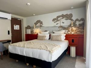 a bedroom with a large bed with a painting on the wall at Hôtel des quatre saisons in Guérande