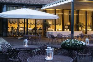 a patio with tables and chairs and a white umbrella at La Colombera Ristorante - Albergo in Castrezatto +40 photos