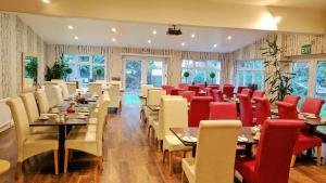 a dining room with tables and red chairs at Avis Hotel in Bromley