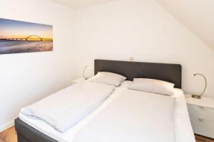 two beds in a white bedroom with a painting on the wall at Bauernhaus Wohnung 1 in Bojendorf
