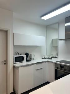 a kitchen with white cabinets and a microwave at Wohnen am St Johanner Markt in Saarbrücken +11 photos