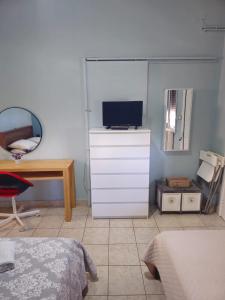 a bedroom with a dresser with a tv and a desk at ΕΥΡΙΠΟΣ in Kritharia