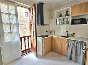 a kitchen with wooden cabinets and a sink and a window at Casa Gelín Verde in Santillana del Mar