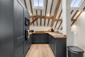 a kitchen with black cabinets and wooden floors at Modern & Historic Duplex Flat Riverside in Godalming