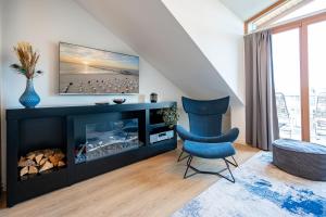 a living room with a fireplace and a blue chair at Villa Linquenda App 6 in Ahlbeck