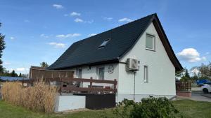 a white house with a black roof at FEWO Am Haussee Feldberger Seenlandschaft in Feldberg