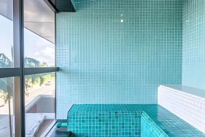 a bathroom with a green tiled tub with a glass wall at BHS Flat a beira mar 2203 in Recife
