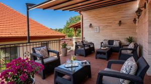 an outdoor patio with chairs and tables and flowers at Hotel Dolce Vita in Balatonkenese