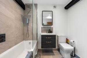 a bathroom with a tub and a toilet and a sink at Modern & Historic Duplex Flat Riverside in Godalming