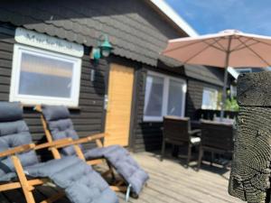 a group of chairs and an umbrella on a deck at Ferienhaus Muckelbude in Bedekaspel