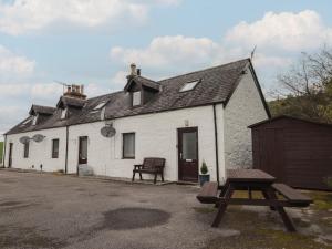 a white building with a picnic table in front of it at 3 Bruaich Cottages in Strathpeffer