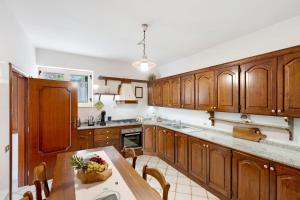 a kitchen with wooden cabinets and a table with a bowl of fruit at Ulivello House Sea View in Massa Lubrense